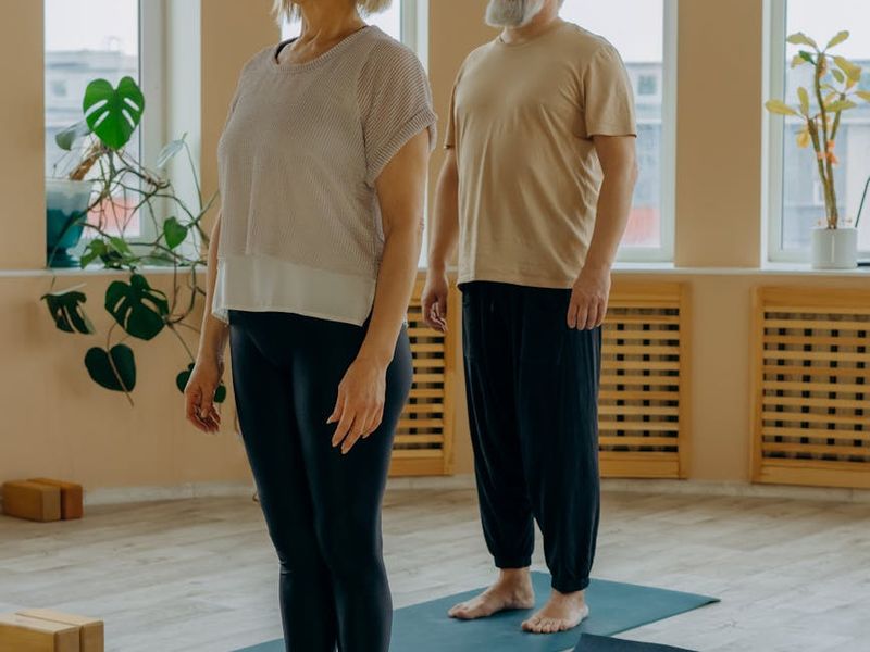 Man stretching on a yoga mat in a bright, sunlit room.